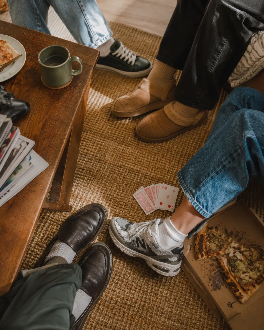 flatmates hanging out on the living-room floor with cards and pizza